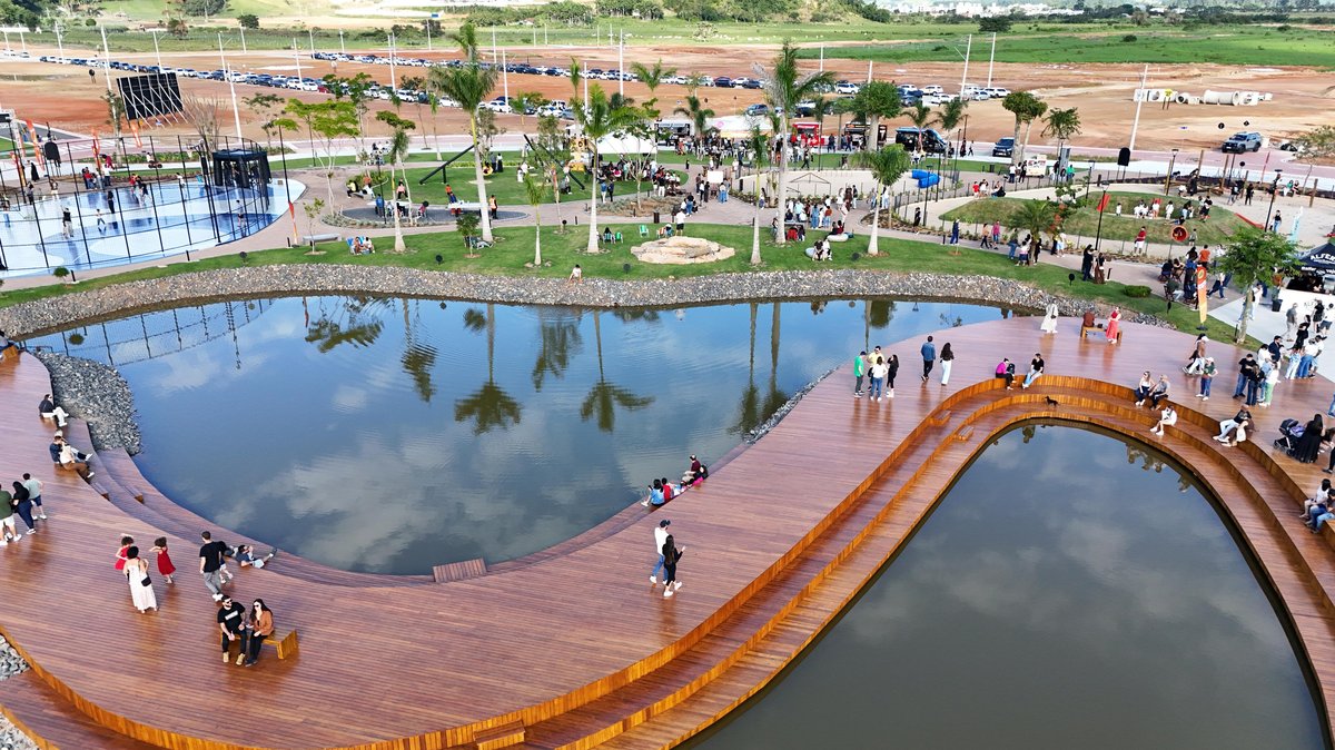 Deck de madeira sobre o lago do Parque Santa Helena, em Tijucas, com famílias caminhando